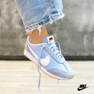 Ténis Nike azul claro com sola castanha e etiquetas NIKE.