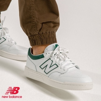Ténis New Balance brancos com detalhes verdes em fundo branco
