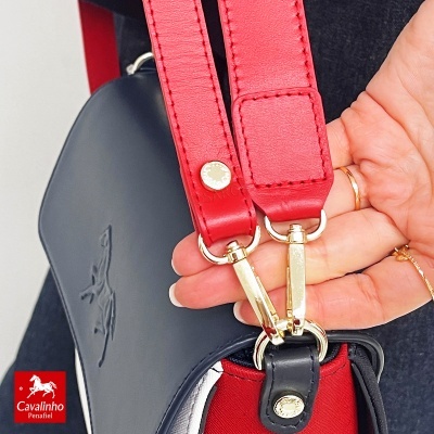 Bolsa preta com faixa vermelha e detalhes dourados na mão