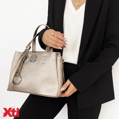 Mulher com mala prateada em pele sintética e blazer preto