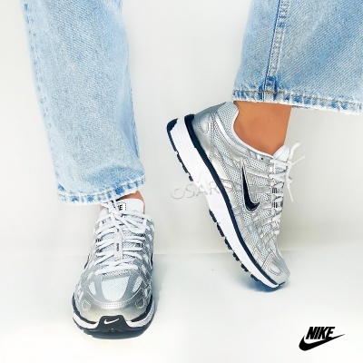 Sapatilhas Nike prata com detalhes pretos e brancos com jeans azuis claros.