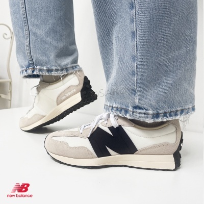 Ténis New Balance branco e bege com sola preta usados com jeans azul claro