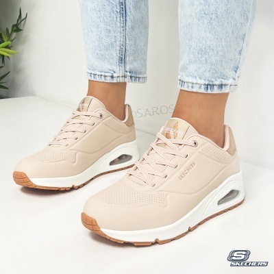 Ténis Skechers bege com sola branca e detalhes castanhos usados com calças de ganga