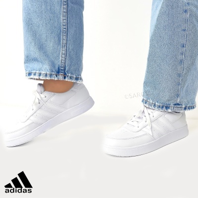 Ténis Adidas brancos com três riscas e jeans azuis