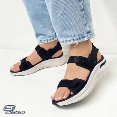 Sandálias Skechers pretas com sola branca e tiras ajustáveis usadas com calças de ganga claras