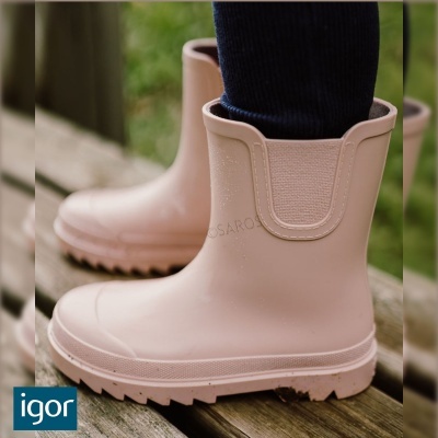 Botas de borracha cor de rosa claro com elástico lateral em superfície de madeira