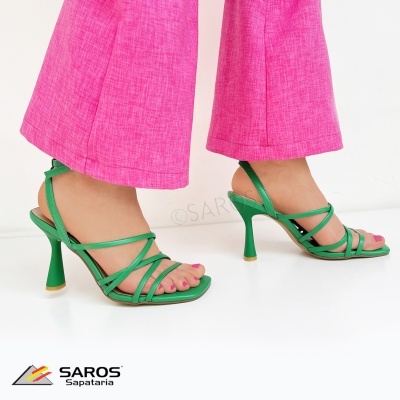Sandálias verdes de salto alto e tiras finas usadas com calças cor-de-rosa