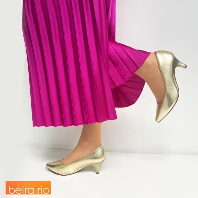 Sapatos dourados de salto médio com saia rosa plissada