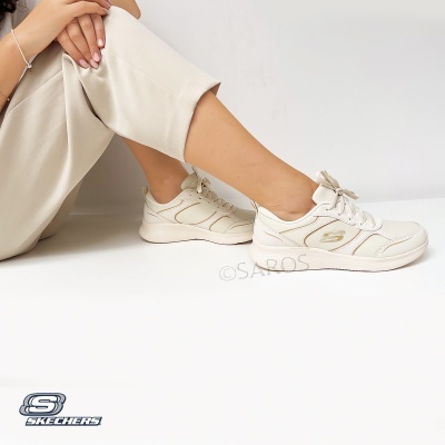 Ténis Skechers bege claro com brilho dourado, sola branca, usados por pessoa com calças bege
