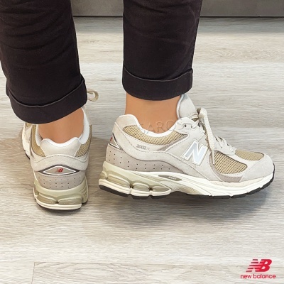 Ténis New Balance 2002R bege e creme com sola branca e logo vermelho
