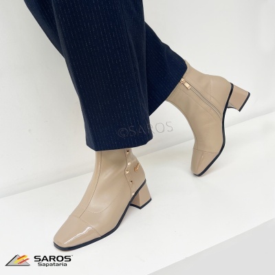 Botas bege com salto médio e fecho lateral usadas com calças pretas