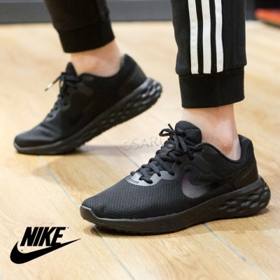 Ténis pretos Nike em piso de madeira interior