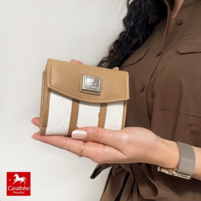 Carteira castanha e branca Cavalinho Penafiel segura por mulher com relógio e anel