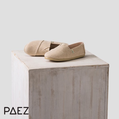 Par de alpercatas bege com textura trançada em cima de pedestal de madeira