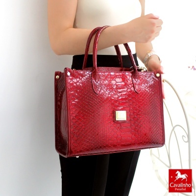 Mala vermelha de pele com padrão de escamas com alças e ferragens douradas