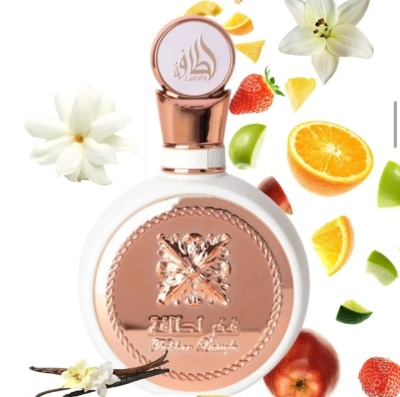Frasco de perfume redondo branco com tampa cobre rodeado por frutas e flores.