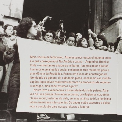 Mulheres numa manifestação segurando cartaz com texto sobre feminismo e direitos humanos em português.