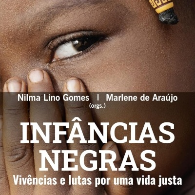 Capa de livro Infâncias Negras com rosto de mulher negra em close e texto branco sobreposto.