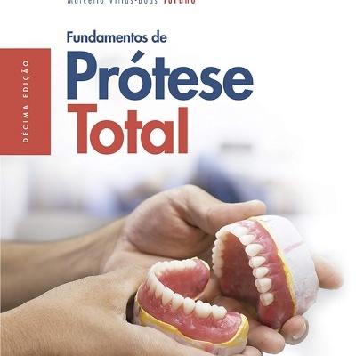 Livro Fundamentos de Prótese Total com próteses dentárias nas mãos