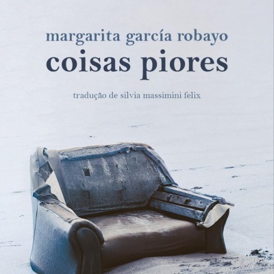 Livro com capa mostrando sofá velho num cenário de praia com areia e texto em azul.
