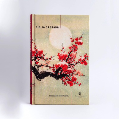 Livro da Bíblia Sagrada capa dura com flores vermelhas sobre fundo bege.