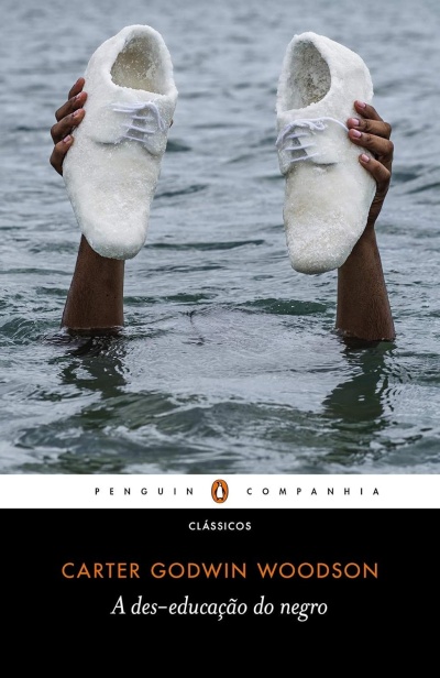 Livro A des-educação do negro com imagem de mãos negras segurando sapatos brancos em água