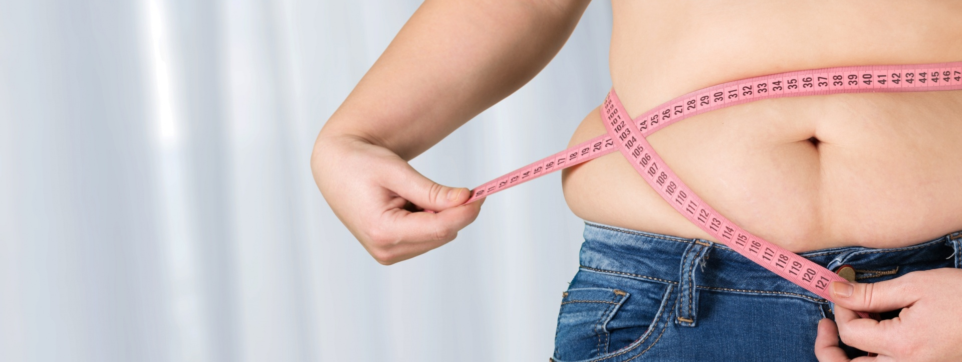 Pessoa a medir cintura com fita métrica cor-de-rosa