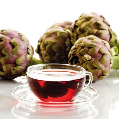 Chá vermelho num copo transparente com quatro alcachofras ao fundo