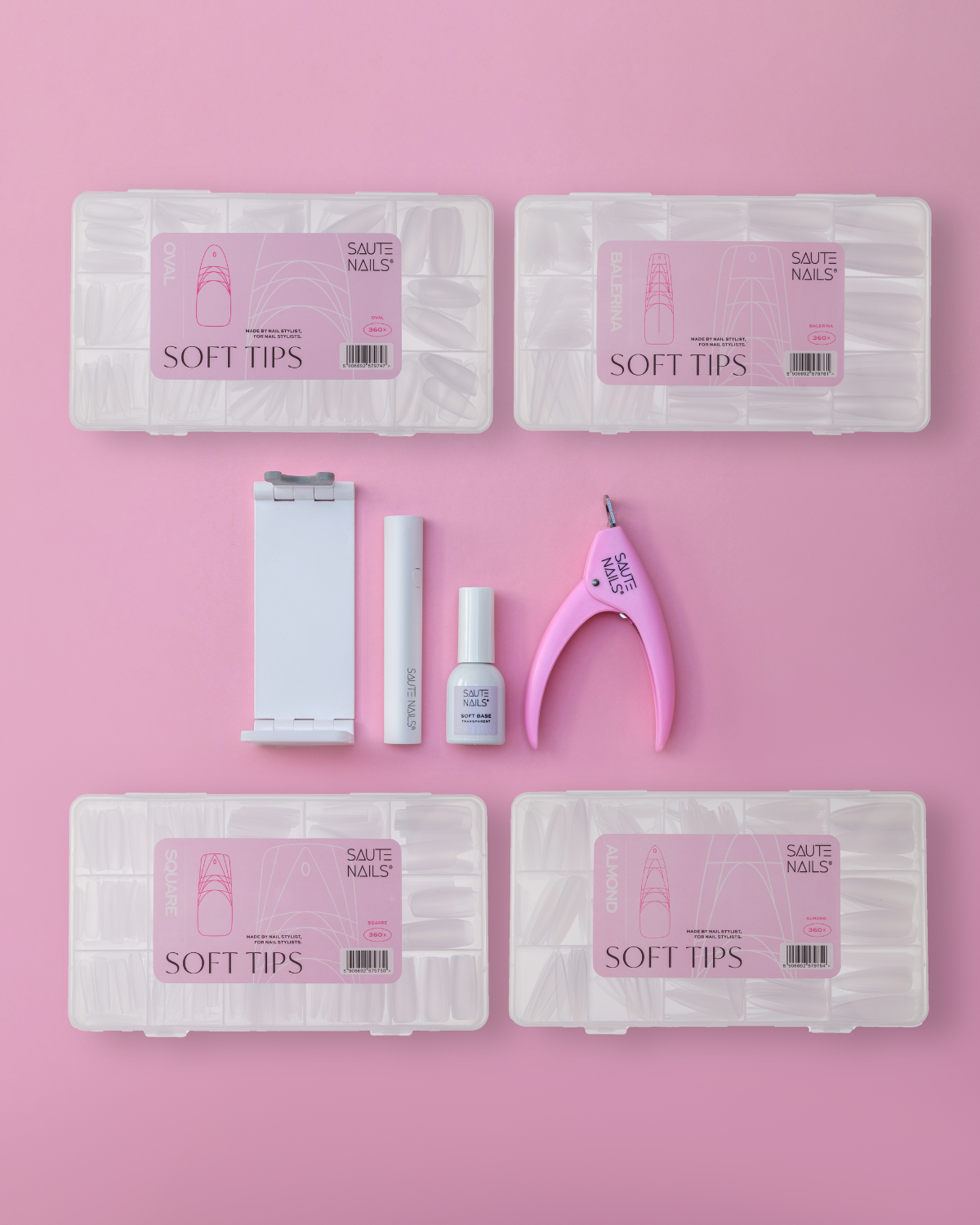 Conjunto Super Completo Soft Tips System XXL (4 formatos) Caixas transparentes de SOFT TIPS, frasco branco, suporte de unhas e alicate rosa sobre fundo rosa.