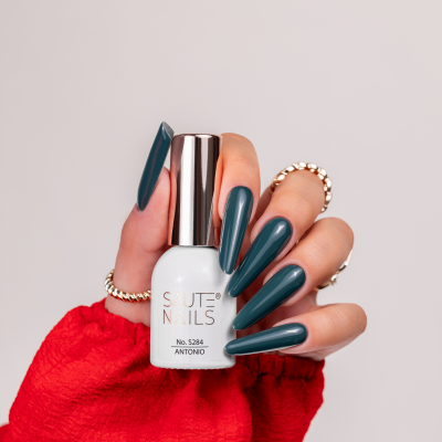 Mão com unhas azuis escuras segurando frasco branco de verniz SAUTE NAILS número 5284