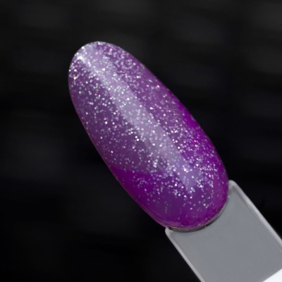 Unha artificial roxa com glitter sobre fundo preto