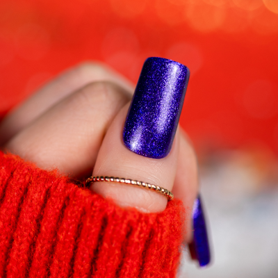 Unha pintada com verniz roxo brilhante e texturizado com camisola vermelha e anel dourado.