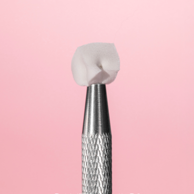 Ferramenta metálica para unhas com ponta de espuma branca e fundo rosa