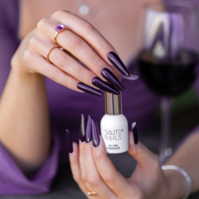 Verniz de unhas SAUTE NAILS com unhas roxas e taça de vinho ao fundo