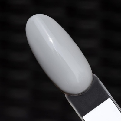 Amostra de verniz branco numa unha artificial com fundo desfocado