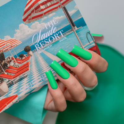 Mãos com unhas verdes foscas segurando cartão com imagem de resort e texto