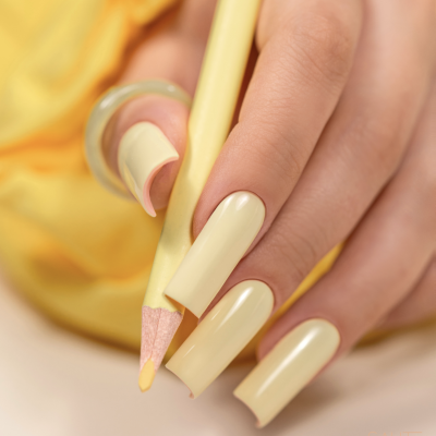 Mão com unhas amarelas segurando lápis amarelo