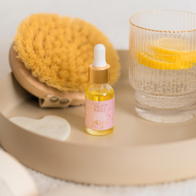 Frasco de sérum, escova e copo com limão numa bandeja bege