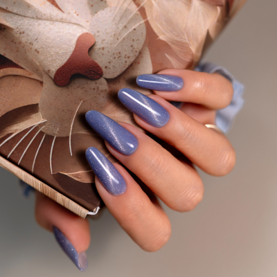 Mãos com unhas azul brilhante segurando caixa com desenho de leão