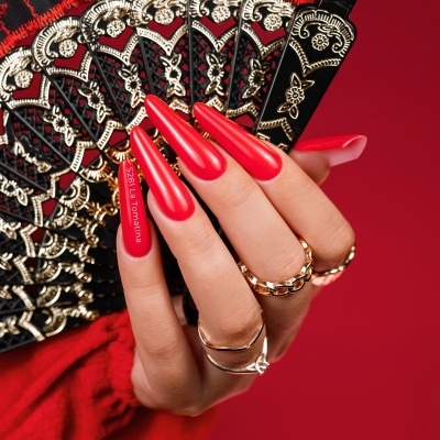 Mão com unhas vermelhas longas segurando leque preto decorado com dourado