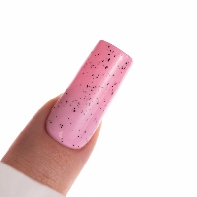 Unha artificial pintada de rosa claro com manchas pretas em fundo branco