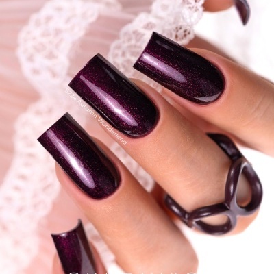 Unhas roxas escuras brilhantes com anel preto e fundo de renda branca