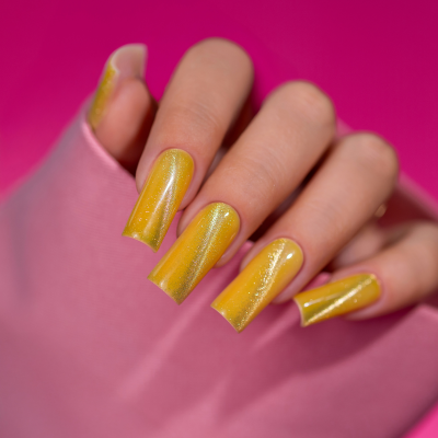 Mão com unhas amarelas brilhantes segurando tecido rosa