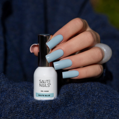 Esmalte azul claro Saute Nails com unhas pintadas na mesma cor sobre tecido azul.