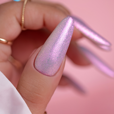 Unhas compridas rosa cintilantes com anéis dourados em fundo rosa.