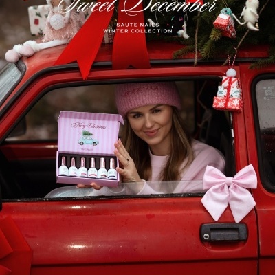 Mulher segura caixa rosa de vernizes Saute Nails dentro de carro vermelho decorado para Natal