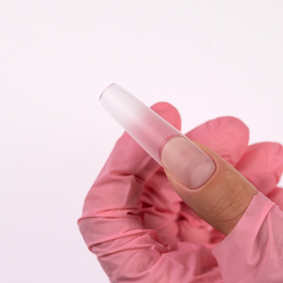 Unha postiça transparente segurada por mão com luva cor-de-rosa sobre fundo branco