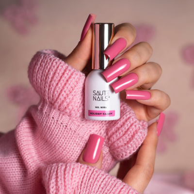Mãos femininas com unhas rosa brilhantes segurando verniz SAUTE NAILS Holiday Candy