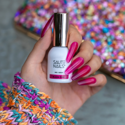 Verniz SAUTE NAILS Glass Pink segurado por mão com unhas compridas cor vinho e roupa colorida