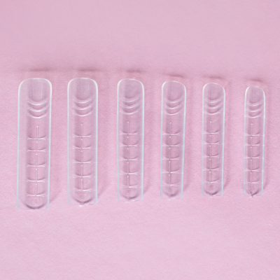 Paletas de plástico transparente em vários tamanhos sobre fundo rosa.